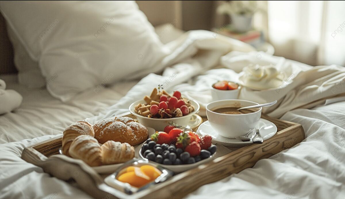 Ontbijt op bed met croissants, fruit en thee